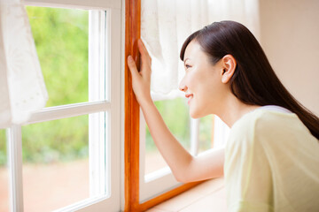 窓から外を眺める女性