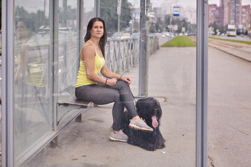 White woman with briard near her waits for tram on public transp