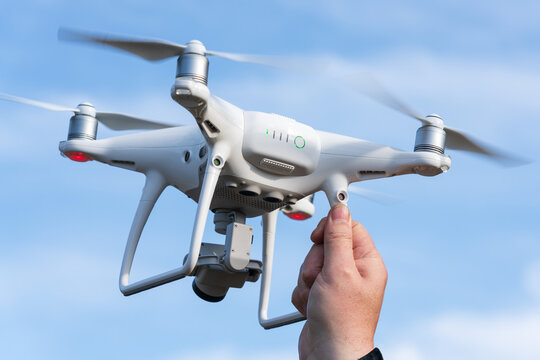 Male hand catches / launches professional drone quad copter DJI Phantom 4 Pro with digital camera 4K on background of autumn blue sky. Kamchatka Peninsula, Russian Far East at September 12, 2019