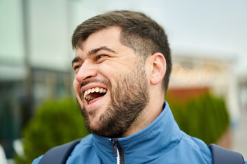 Obraz premium Handsome caucasian man with beard walks outdoors and smiles.