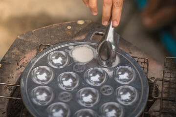 blurred abstract background of making desserts through a stainless steel stove with holes (Kanom Krok)is a traditional dessert made with coconut milk and sugar and then heated until the food is cooked