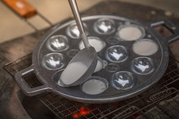 blurred abstract background of making desserts through a stainless steel stove with holes (Kanom Krok)is a traditional dessert made with coconut milk and sugar and then heated until the food is cooked