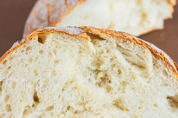 A slice of white fresh crispy bread on a brown background