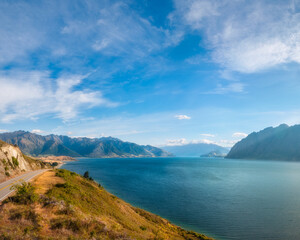 Fototapeta premium Lake Hawea Vertical Panorama in beautiful morning light with mountain peaks in the distance in Otago Region, New Zealand, Southern Alps.