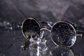 Fototapeta na wymiar Sunglasses with water splashes on a silver background
