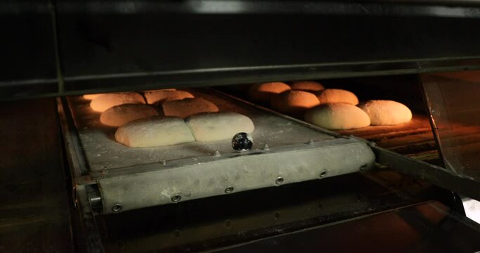 Moving The Raw Bread Dough Into The Pre-Heated Deck Oven Using A Handheld Manual Loader- Closeup Shot