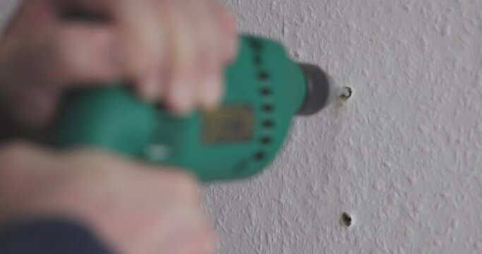 man is drilling holes in the wall with a drilling machine