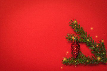 A green spruce branch with a red glass cone on a red background.