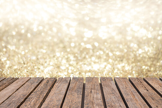 rustic old wood table in front of glitter silver and gold bright bokeh lights for display products. wall background.