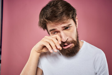 bearded man in white t-shirt emotions displeased facial expression studio pink background