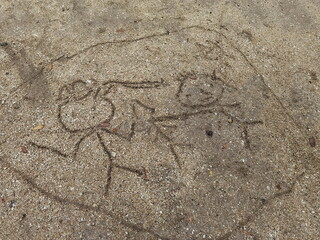 A family drawing on the sand by a child. It consists of parents and children in the daytime when it is sunny.