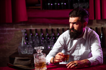 Man with beard holds glass brandy. Bearded guy drink cognac. Man holding a glass of whisky. Sipping whiskey. Portrait of man with thick beard. Macho drinking. Degustation, tasting.