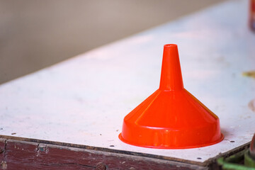 Red Plastic funnel on table.