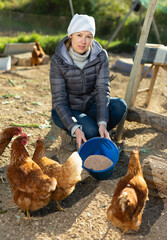 Woman farmer feeding bird in the backyard of a village house. High quality photo © JackF
