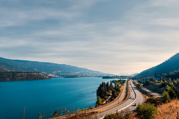 Top view of the highway with moving cars, river and hills