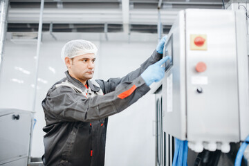 Male operator engineer controls production line from control panel, food factory