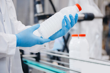 Man worker holding milk bottles production line dairy factory industry, automatic conveyor for...