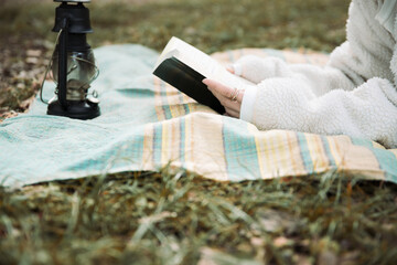 森の中でレジャーシートに寝転びながら本を読む女性