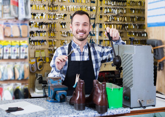 Male worker demonstrating newly shaped key in workshop