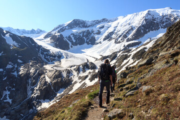 Group of people hiking towards glacier Taschachferner and mountain snow panorama with blue sky in Tyrol Alps, Austria