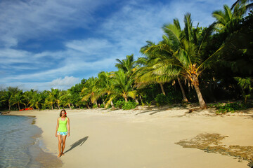 Fototapeta na wymiar Young woman walking on a beach on Drawaqa Island, Yasawa Islands, Fiji