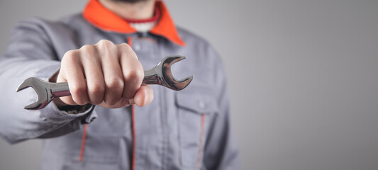 Man wearing a uniform holding a wrench.