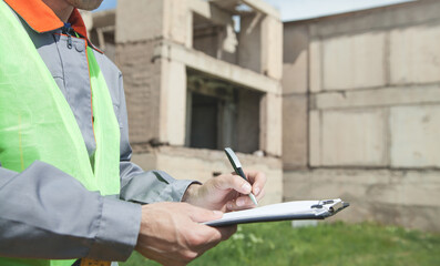 Construction worker writing on clipboard.