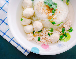 Clear Pork Noodle Soup Topped with pork balls Garnish with fried garlic and cilantro