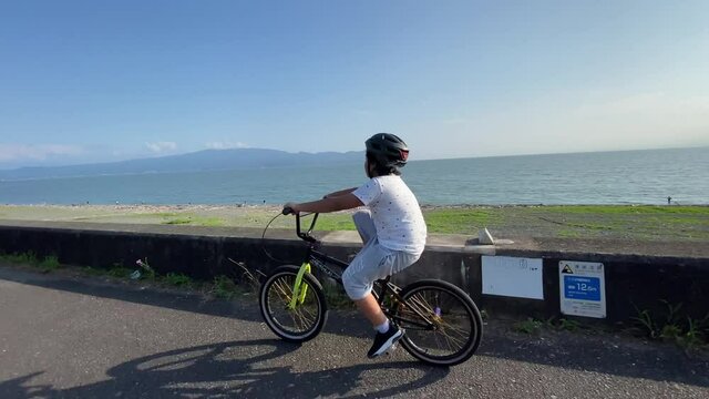 A kid riding his bmx near the beach at Numazu in Japan.