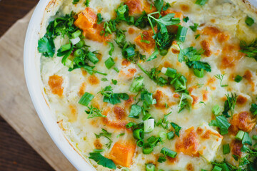 Top view of a traditional pumpkin pie with turkey and baked vegetables in a white dish on a wooden...