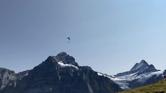 paraglider flying over snowy mountains on a blue sky