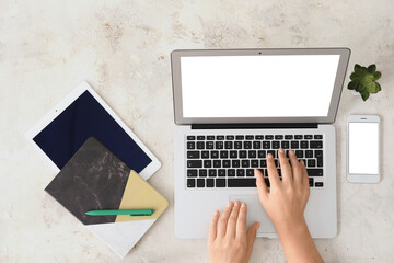 Female hands with modern laptop on light background
