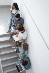 Students with modern devices on stairs at the university