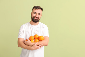 Man with oranges on color background