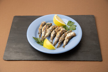 fried sardines, in blue plate with lemon wedge
