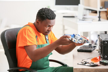 African-American technician repairing computer in service center