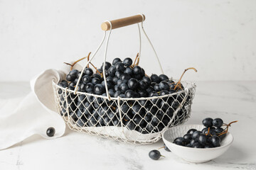 Basket and bowl with sweet ripe grapes on table