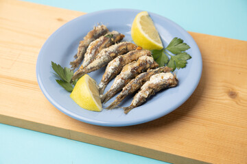 fried sardines, in blue plate with lemon wedge
