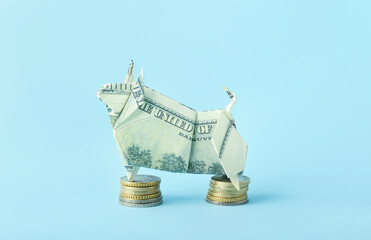 Origami bull as symbol of year 2021 and coins on color background
