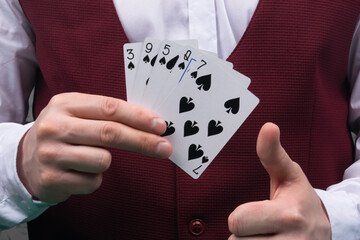 the croupier holds the winning combination of cards in one hand, and on the other hand, the thumb is raised to the top