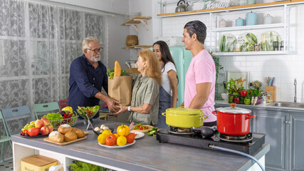 Elderly parent or senior adults having good time with their children cooking foods together at home