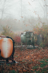 old farm equipment sitting in a field with a drape of fog around 