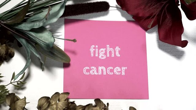 Lay Flat View-FIGHT CANCER digitally written on a piece of pink cardstock on a white canvas backdrop with blue, green and burgandy floral accents