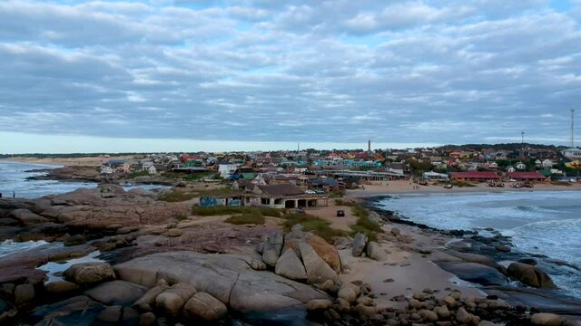 Drone ascending on hard rocks shore in a costal fisherman's town in Rocha, Uruguay