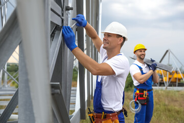 Workers building high voltage tower construction outdoors. Installation of electrical substation