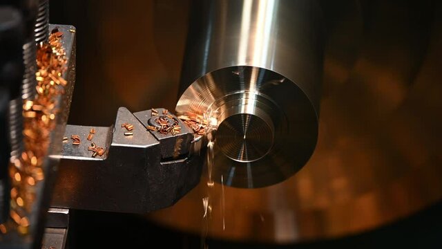 Close-up scene operation of lathe machine cutting the brass shaftl parts and the cutting chips. The metalworking process by turning machine.
