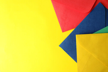 Fototapeta na wymiar Colorful paper envelopes on yellow background, top view. Space for text