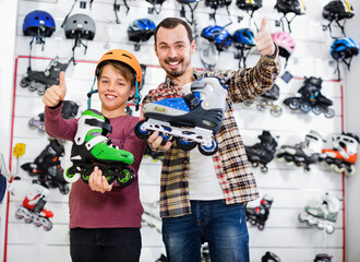 Satisfied smiling father and son enjoying purchased roller-skates in sports store