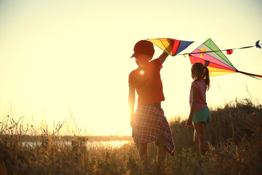 Little children playing with kites outdoors at sunset. Spending time in nature