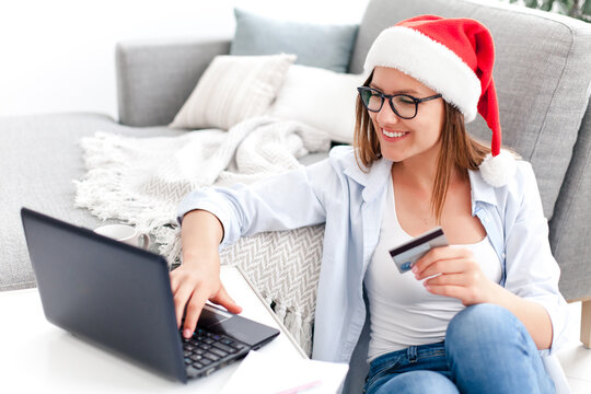 Christmas Shopping Online At Home. Happy Woman Buying Holiday Gifts With Laptop During Covid Quarantine. Girl Paying By Credit Card And Enjoying Purchases In The Internet On Black Friday.